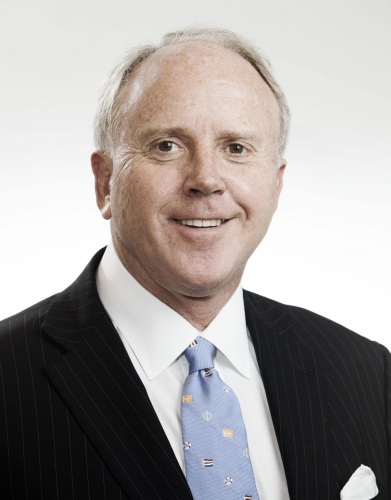 Headshot of Bracebridge Young wearing a black suit with a light blue, sailing-themed tie.
